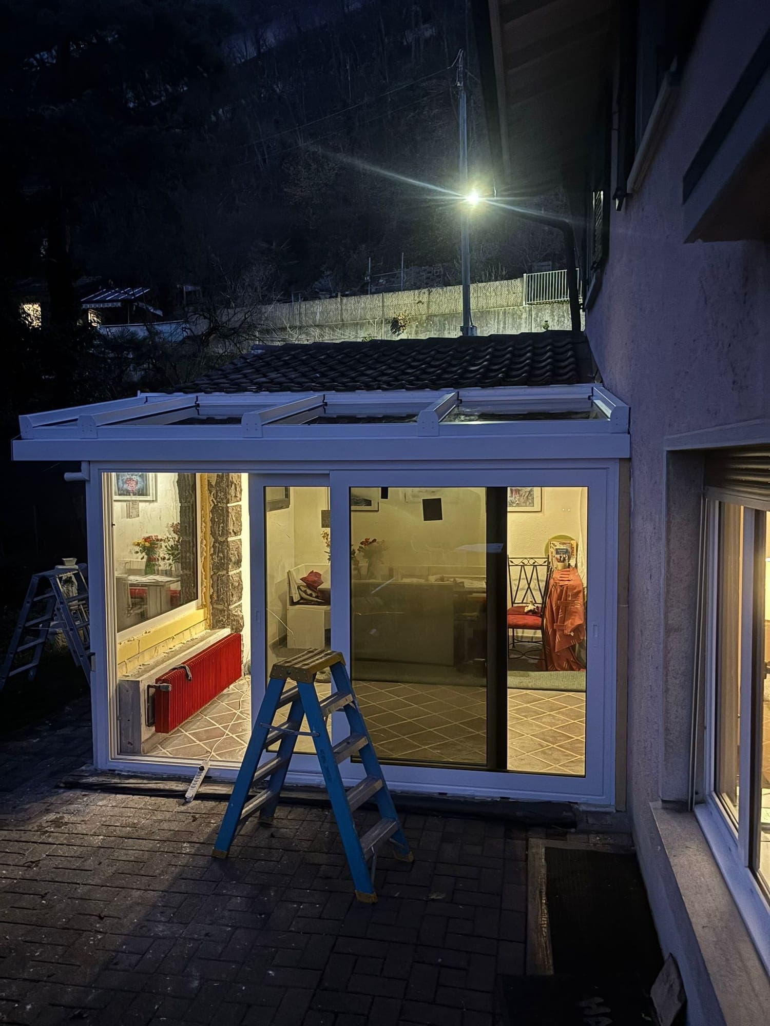 Véranda blanche éclairée de l'intérieur à la tombée de la nuit